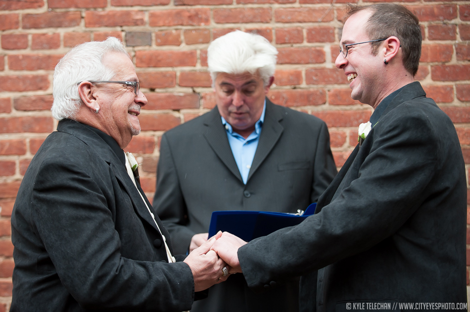 Partners Bobby, on left, and Nicky Stavitzke-Samar smile at each other as Jim Bilow pronounces them married during their wedding ceremony in downtown Crown Point on Friday.